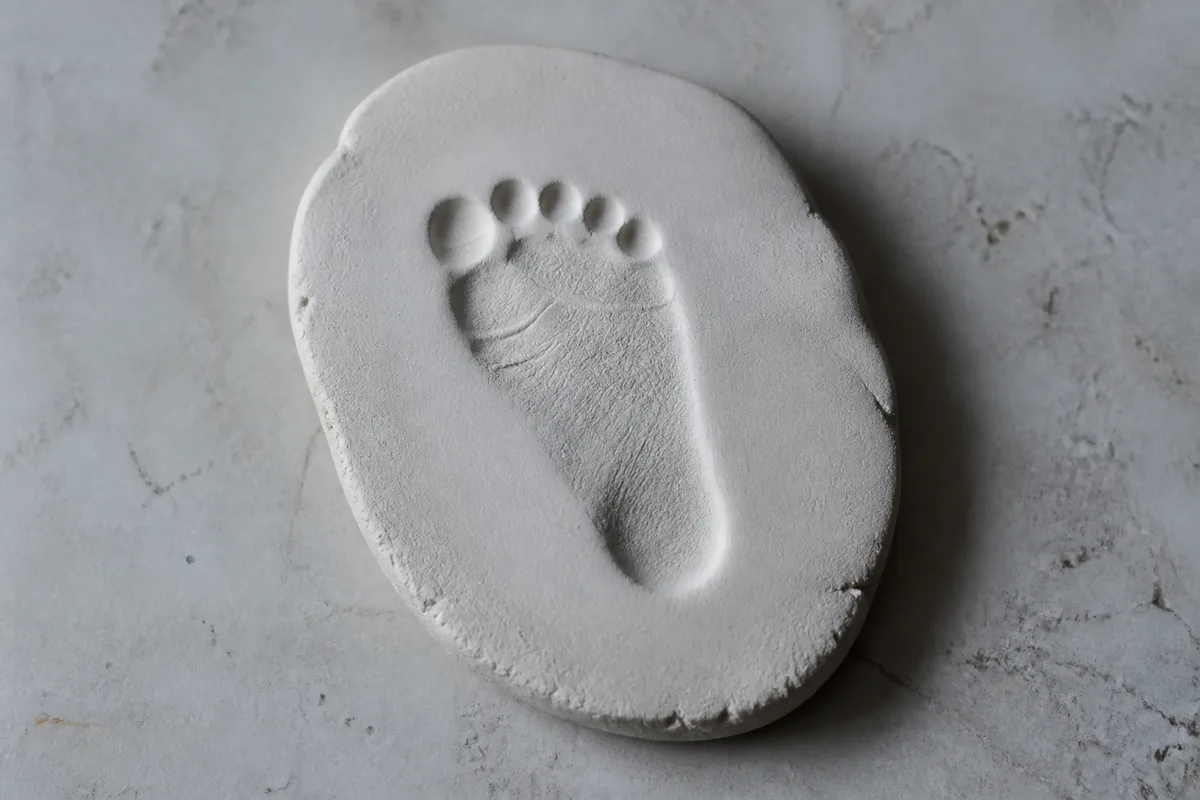 Empreinte de pied dans une pâte blanche autodurcissante posée sur un plan de travail clair